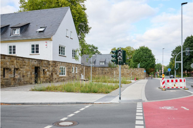 Copyright:  Stadt Münster/Phillina Zuther - der Raum vor der Sandsteinmauer ist kaum wiederzuerkennen. Der Verkehr der Roxeler Straße ist an das Oxford-Quartier angebunden, die Veloroute ist ausgebaut und auf dem begrünten Vorplatz ist eine kleine Mobilstation entstanden.